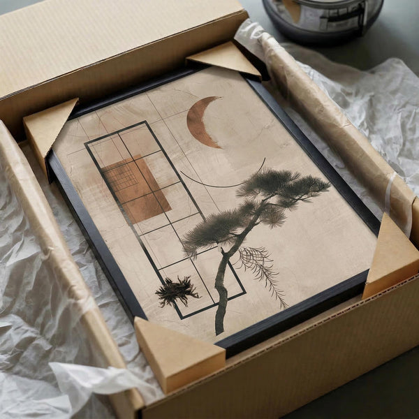 Framed abstract art print featuring a geometric pine tree with overlapping rectangular shapes and a crescent moon, displayed in a black frame being unboxed from brown cardboard packaging with white tissue paper protection