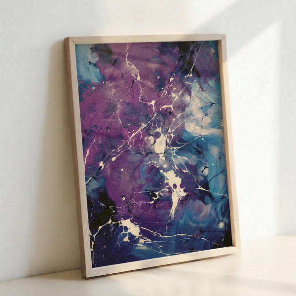 May include: Framed abstract artwork leaning against white wall, featuring fluid purple and blue watercolor-style paint with cream colored splatter patterns and crackling texture throughout. Natural wood frame surrounds the vertical rectangular print, which shows organic flowing shapes and cosmic-like speckled details against the colorful background.