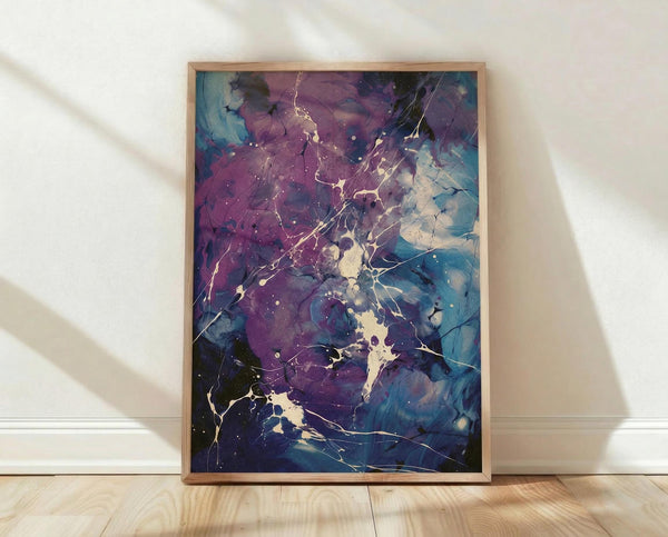 May include: Framed abstract art print leaning against white wall on light wood floor. Artwork features fluid paint splatters and marbled textures in deep purples, blues, and teals with golden cream accents and delicate white linear details throughout. Natural wood frame surrounds the vertical rectangular print. Soft natural lighting creates gentle shadows on the wall.