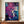 May include: Framed abstract art print featuring vibrant purple and blue fluid paint splatters with white lightning-like cracks and golden accents, displayed on wooden sideboard next to cream ceramic vase and stacked books in elegant room with cream wainscoting walls.