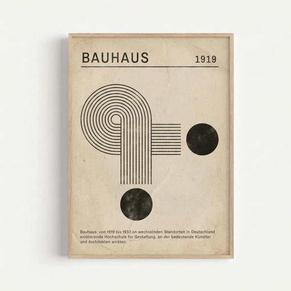 Framed vintage-style poster with cream textured background featuring black geometric design including curved concentric lines forming an arch shape, horizontal parallel lines in a rectangle, and two solid black circles. Text reads "BAUHAUS 1919" at top with German description at bottom. Natural wood frame against white wall.