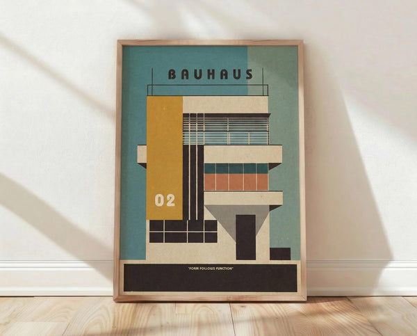 May include: Framed modernist architectural poster featuring geometric building illustration in teal, yellow, orange and cream colors with "BAUHAUS" text and "02" numbering. Wood frame leaning against white wall on light wooden floor with natural window shadows.