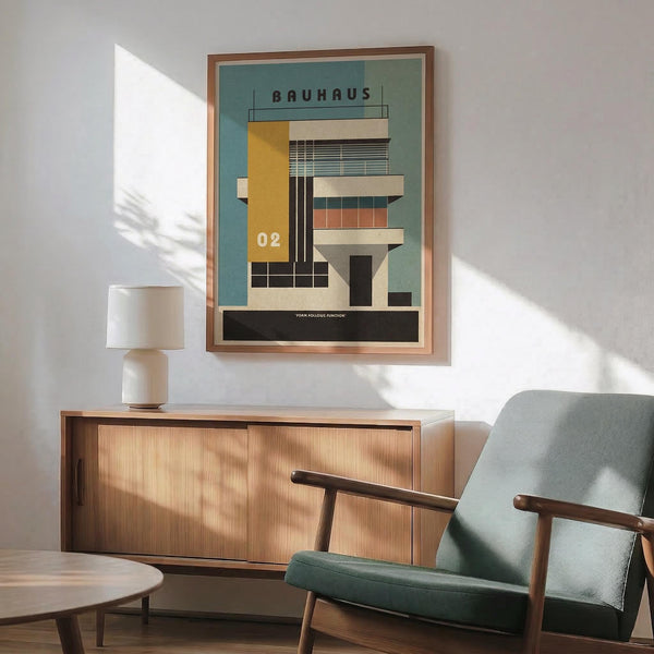 May include: Modernist architectural poster with teal background showing geometric building design in yellow, white, and black. Features "Bauhaus" text and "02" numbering. Displayed in thin copper frame above wooden sideboard with white ceramic lamp. Mid-century modern sage green armchair with wooden arms in foreground. Bright natural light creates shadows across white wall.
