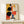 May include: Modern abstract geometric poster in light wood frame displayed on white dresser against cream wall. Features bold circles in black, red, and orange, with rectangular shapes in yellow, blue, and beige arranged in Bauhaus style composition. Small wrapped gift with pine sprig sits beside frame. Natural lighting creates soft shadows on minimalist room setting.