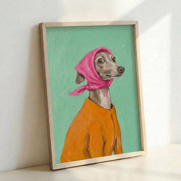 May include: Framed painting of an Italian Greyhound wearing a bright pink headscarf and orange coat, painted in a portrait style against a mint green background. The artwork is displayed in a natural wood frame leaning against a white wall on a light surface, showing visible paint texture and brushstrokes.