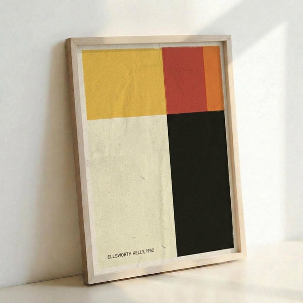 May include: Abstract geometric art print in light wood frame leaning against white wall. Artwork features four color blocks - yellow upper left, red and orange upper right, cream/white lower left, and black lower right. Artist attribution "ELLSWORTH KELLY, 1952" printed in small black text on cream section. Simple minimalist composition with clean lines and bold color contrast.