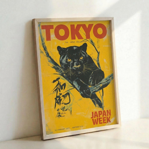 May include: Vintage-style poster with yellow background featuring black panther with golden eyes perched on tree branch, red "TOKYO" text at top, Japanese characters on left side, "JAPAN WEEK" in red at bottom right, dated February 1977, displayed in light wood frame leaning against white wall