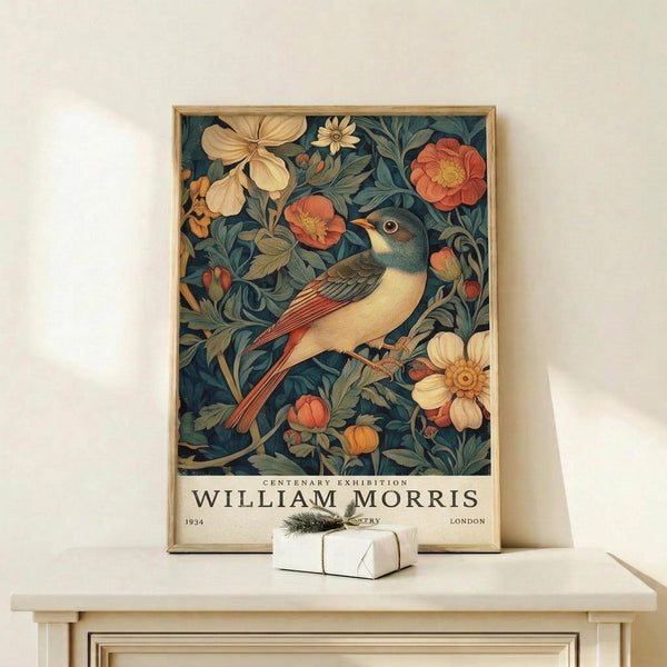 May include: Framed vintage-style botanical poster featuring a colorful bird perched among flowers and foliage in William Morris decorative art style, displayed on light wood console table with small wrapped gift, against cream wall with natural lighting
