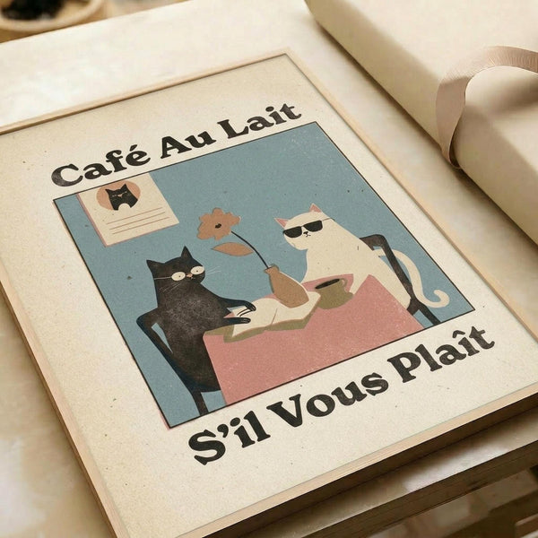 May include: Vintage-style illustrated poster featuring two cats at a cafe table - a black cat and white cat with sunglasses sharing coffee and a flower. Text reads "Cafe Au Lait" and "S'il Vous Plait" in retro typography. Soft blue, pink, and cream color palette with textured paper appearance. Print displayed in white matted frame on neutral surface with ribbon visible.