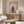 May include: Framed poster featuring a cream-colored poodle wearing a teal turtleneck sweater against a soft pink background, with "DOGUE" text at top in orange letters. Displayed on a walnut wood sideboard in a modern living room with white upholstered chair, glass coffee table, and neutral decor.