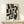 May include: Black and white abstract geometric artwork in light wood frame, displayed on pale wooden console table against cream wall. Small wrapped gift box with greenery sits nearby. Bold brushstroke patterns create interlocking angular shapes across white canvas background.