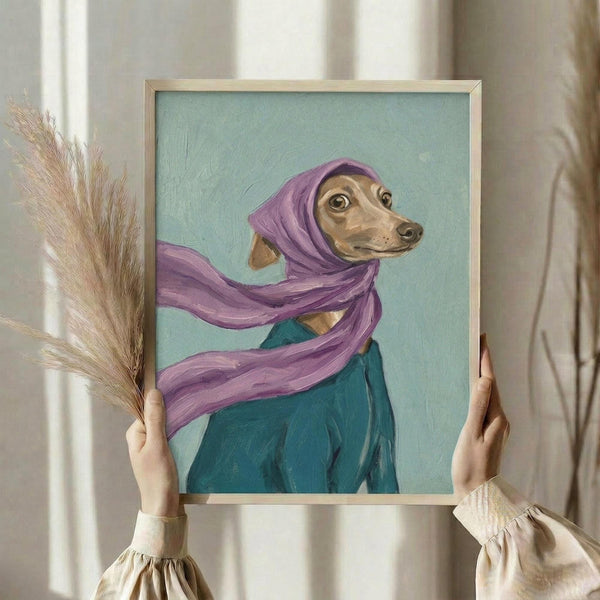 May include: Hands holding a framed painting of a tan Italian Greyhound wearing a flowing purple headscarf and teal garment against a mint green background. The artwork is in a light wood frame, held alongside dried pampas grass stems in a bright room with white curtains and neutral walls.