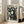 May include: Large framed vintage-style poster featuring stylized black cats with white eyes and whiskers against cream background, displayed on wooden floor next to beige sectional sofa in bright living room with white walls and large windows, natural sunlight streaming across hardwood floors