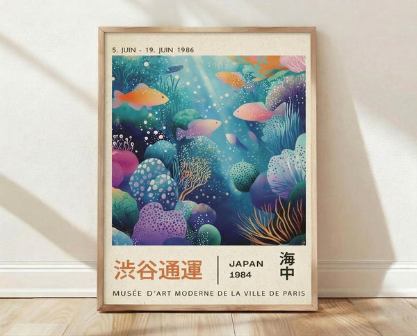 May include: Framed poster with vibrant underwater scene featuring colorful fish, coral, and sea plants in blues, purples, oranges and greens. Text shows Japanese characters and "JAPAN 1984" with museum attribution. Light wood frame against white textured wall on wooden floor with soft shadows.