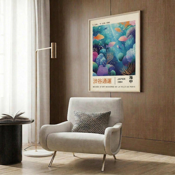 May include: Framed underwater scene poster with colorful coral reef and tropical fish in blues, purples, and oranges, displayed above a beige upholstered armchair with geometric patterned pillow. Modern brass floor lamp and dark side table with open book complete the contemporary living room setting against wood-paneled wall.