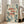 May include: Framed art print leaning against white wall next to beige upholstered chair. The artwork features three red and coral-colored fish with large dark eyes and dotted patterns, surrounded by teal green foliage, cream-colored flowers, and scattered circular dots on a light background. The print has a light wood frame and displays a vintage botanical illustration style with muted, earthy tones.