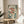 May include: Framed artwork featuring three red fish with white spotted patterns and large eyes, surrounded by teal green seaweed and cream-colored flowers with dotted bubbles on a light background. The print sits on a round wooden side table next to a beige upholstered chair, with a plant visible in soft natural lighting from a window.