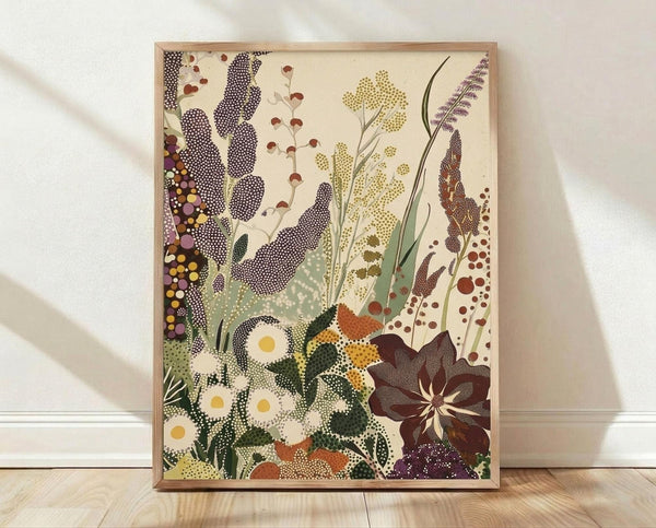 May include: Framed botanical art print featuring stylized wildflowers and plants in dotted pattern style, displayed against white textured wall on light wood floor. Artwork shows purple feathery plumes, white daisies with yellow centers, tall grasses, and various meadow flowers in earthy tones of green, brown, purple and yellow on cream background, housed in thin natural wood frame.