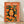 May include: Framed poster with orange background featuring stylized woman with black hair surrounded by oranges, orange slices, and green leaves. Text reads "TOKYO - JAPAN" at top with Japanese characters at bottom. Wooden frame sits on light wood floor against white wall with fabric shadows visible.