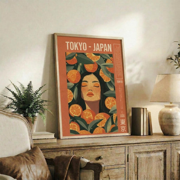 May include: Orange vintage-style travel poster featuring woman with dark hair surrounded by citrus fruits and green leaves, displayed in light wooden frame on rustic wooden sideboard next to fern plant, books, and ceramic vessels in bright living room setting