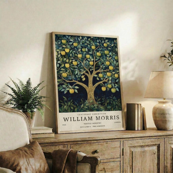 May include: Framed vintage-style poster featuring a decorative tree with yellow fruit and green foliage on dark blue background, displayed on rustic wooden sideboard alongside fern plant, ceramic vase, and books in neutral-toned living room setting with cream upholstered furniture