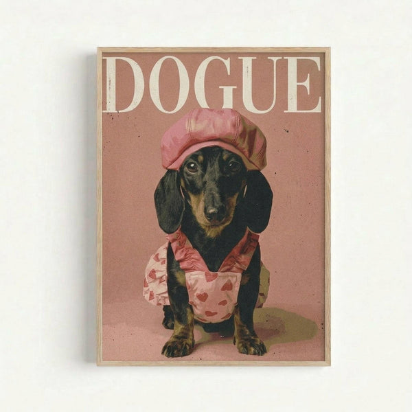 Framed poster featuring a dachshund wearing a pink chef's hat and heart-patterned apron against a dusty rose background. The word "DOGUE" appears in large cream letters at the top, mimicking fashion magazine styling. The black and tan wiener dog sits posed like a model, with the artwork having a vintage, slightly textured appearance in warm pink and beige tones within a light wood frame.