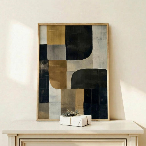 May include: Abstract geometric artwork in natural wood frame displaying overlapping curved and rectangular shapes in navy blue, mustard yellow, gray, and cream tones with textured brushwork effects, displayed on light wood console table beside small white wrapped gift with natural greenery accent against cream wall