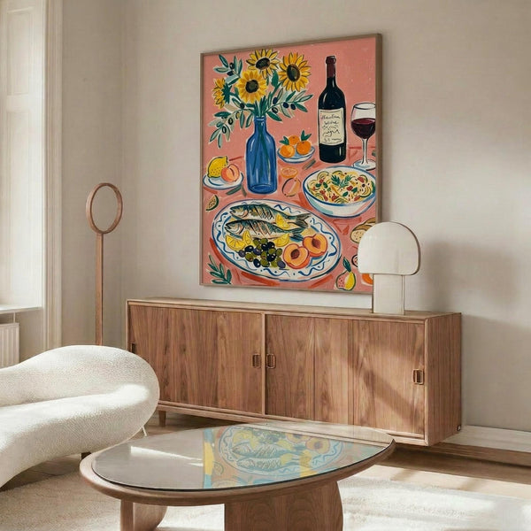 May include: Colorful still life poster with coral pink background featuring sunflowers in blue vase, wine bottle and glass, fish platter with olives and fruit, and pasta bowl, displayed above mid-century walnut credenza in modern living room with cream chair, glass coffee table, and white mushroom lamp