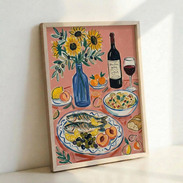 May include: Framed art print leaning against white wall showing colorful still life illustration with coral pink background. Features blue vase with yellow sunflowers, wine bottle and glass, decorative plate with whole fish, lemons and olives, bowls of pasta and fruit, olive branches. Painted in vibrant Mediterranean style with natural wood frame.
