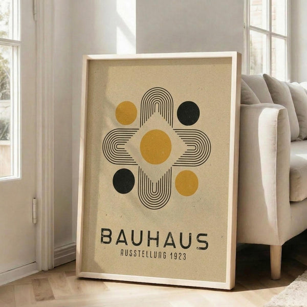 May include: Large framed poster with geometric design featuring yellow and dark green circles connected by black curved lines forming a cross pattern on cream textured background, displayed on wooden floor against white wall next to beige upholstered chair near bright windows in modern living room setting.
