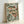May include: Framed botanical art print leaning against white wall showing three speckled fish swimming among green aquatic plants and coral-colored dots on pale mint background, displayed in light natural wood frame