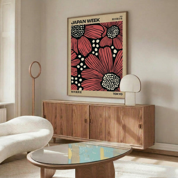 May include: Framed vintage-style poster with bold pink and coral flower design on black background with white polka dots, displayed above mid-century walnut credenza in modern living room setting with cream upholstered chair, brass floor lamp, oval glass coffee table, and neutral wall paint