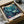 May include: Framed underwater scene artwork in cardboard shipping box with protective wrapping. Features stylized whales, coral, and sea life in teal, blue, and purple tones. Japanese text visible on white border. Artwork appears gallery-ready in black frame, nestled in brown packaging materials on white surface.