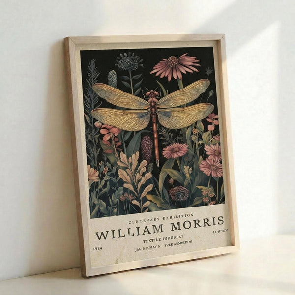 May include: Framed botanical poster featuring a detailed dragonfly with golden wings surrounded by wildflowers and plants in muted pink, green, and cream tones against a dark background. The vintage-style print includes exhibition text at the bottom mentioning William Morris, 1934, and London. Light wood frame displayed leaning against white wall with soft natural lighting creating gentle shadows.
