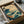 May include: Japanese-style wave artwork in wooden frame being unboxed from cardboard packaging with protective wrapping. Features stylized ocean waves in teal and green with white foam, birds in flight, and traditional Asian aesthetic on cream background. Frame has natural wood finish and appears medium-sized compared to packaging materials.