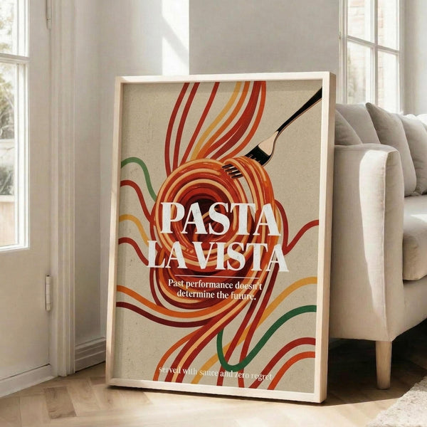 May include: Framed retro-style poster with colorful swirling pasta noodles in red, orange, yellow and green against cream background. White text reads "PASTA LA VISTA" with smaller text below. Black fork visible among pasta swirls. Light wood frame leaning against white wall next to beige upholstered chair in bright room with large windows.