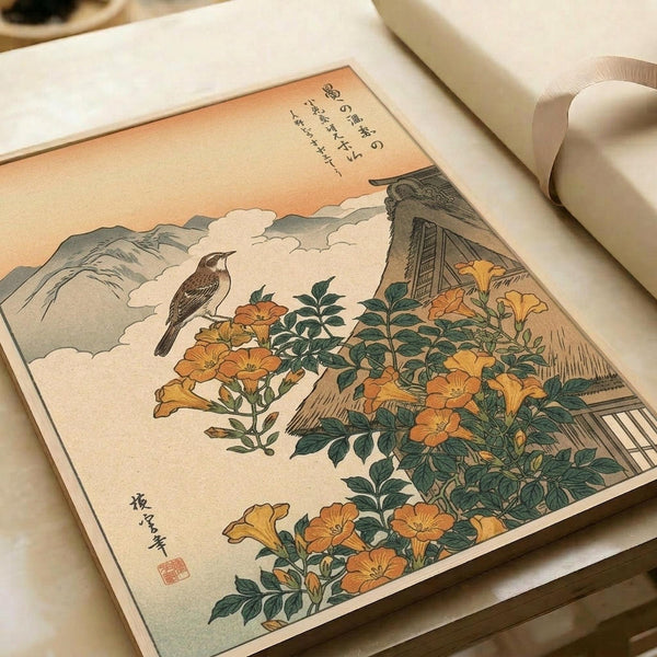 Japanese woodblock print displayed in an open art book showing a brown bird perched among orange trumpet vine flowers with green leaves. Mountains and traditional thatched-roof buildings appear in the background under a peachy sunset sky. The vintage print features delicate linework and muted earth tones typical of traditional ukiyo-e style, with Japanese calligraphy and a red artist seal visible on the cream-colored paper.