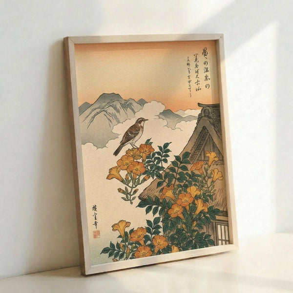 A framed Japanese woodblock print depicting a brown bird perched above orange trumpet vine flowers with green foliage. Mountains and clouds fill the background under a peachy sky, with traditional Japanese calligraphy in the upper right corner and artist's seal at bottom left. The artwork is displayed in a light wood frame against a white wall.