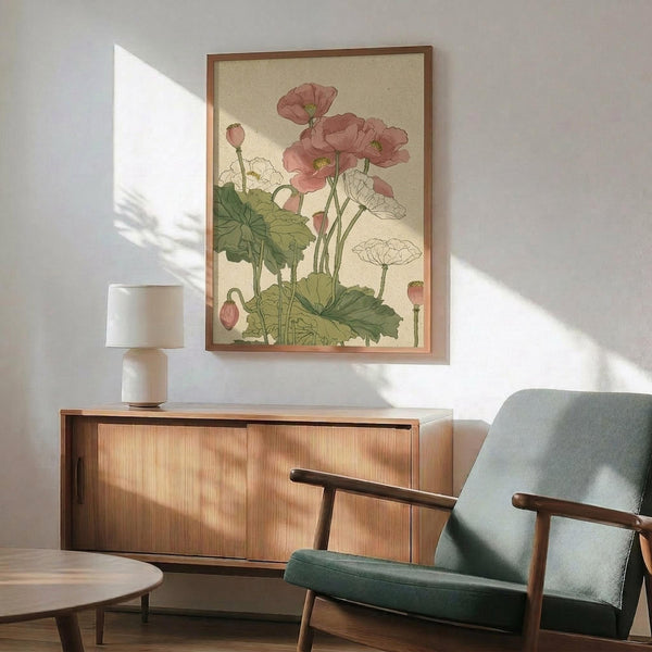 May include: Framed botanical print displaying pink poppies with green leaves and stems in vintage Japanese art style, hanging above a wooden sideboard with table lamp. Mid-century modern teal upholstered chair with wooden arms sits nearby on hardwood floor, with natural sunlight casting shadows across white wall.
