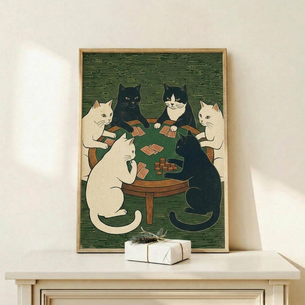 May include: Framed print showing five cats sitting around a green felt card table playing poker in woodblock print style. Three white cats and two black cats (one with white markings) hold playing cards with poker chips on table. Green textured background, wooden frame, displayed on light wooden shelf next to small wrapped gift with twine bow.