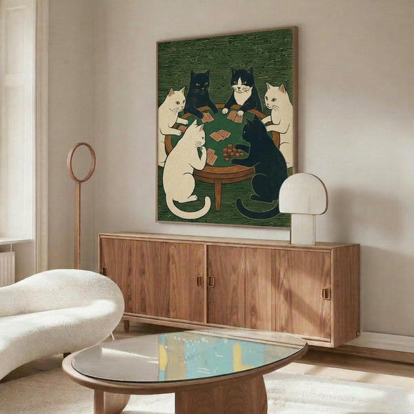 May include: Framed poster showing six cats gathered around a round wooden table playing cards on green textured background. White, black, and tuxedo cats sit on wooden chairs holding cards with poker chips on table. Artwork hangs above mid-century walnut credenza in modern living room with cream upholstered chair, glass coffee table, and white table lamp.