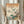 May include: Person in cream clothing holding framed Japanese woodblock print featuring blue bird perched on cherry blossom branch with Mount Fuji in background, surrounded by pink flowers and green leaves, displayed against white curtained window with dried pampas grass visible to left side.