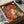 May include: Colorful abstract dog illustration artwork in black frame, packed in cardboard shipping box with protective tissue paper. Four stylized dogs in orange, white, yellow and blue with geometric shapes and vintage texture effects on warm red-orange background. Wooden corner protectors visible in packaging.