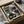 May include: Black and white poster featuring stylized cat faces with halftone dot patterns, displayed in dark frame inside cardboard shipping box with protective tissue paper. Japanese text visible at top and bottom of print. Wooden dowels and packaging materials surround the framed artwork on neutral surface.