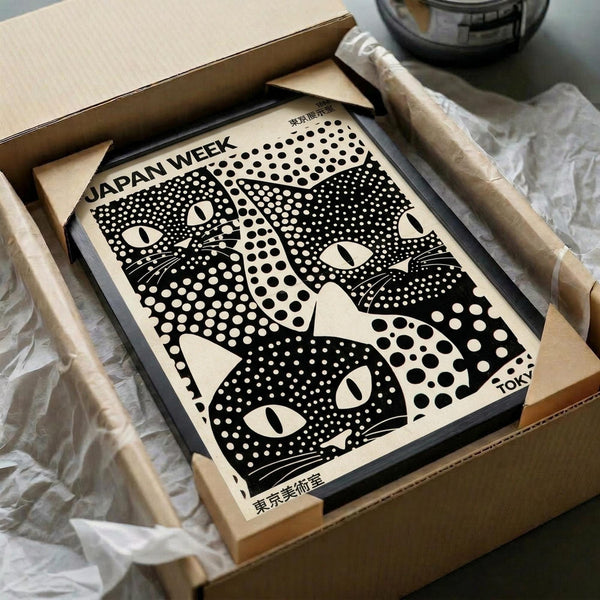 May include: Black and white poster featuring stylized cat faces with halftone dot patterns, displayed in dark frame inside cardboard shipping box with protective tissue paper. Japanese text visible at top and bottom of print. Wooden dowels and packaging materials surround the framed artwork on neutral surface.