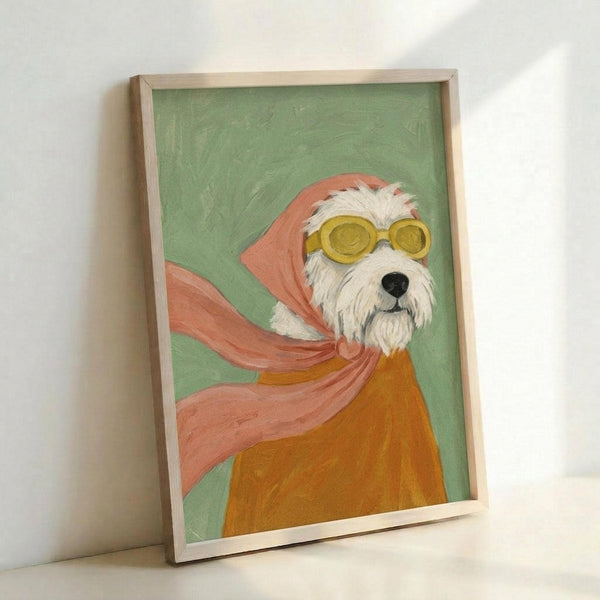 May include: Framed artwork leaning against white wall showing a white terrier dog wearing yellow goggles and coral pink flowing scarf against sage green background. The dog appears in an orange sweater or coat. Painted in a whimsical, illustrative style with visible brushstrokes. Natural wood frame surrounds the canvas artwork.
