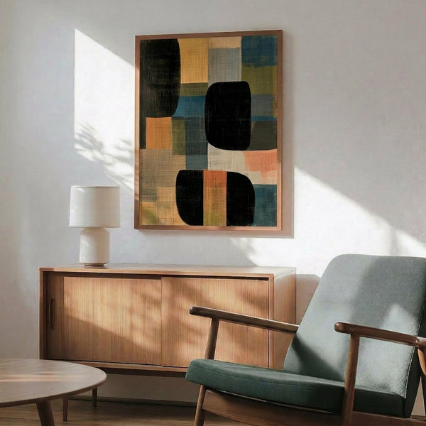May include: Abstract geometric artwork with overlapping colorful rectangles and black rounded shapes in wooden frame, displayed above mid-century modern walnut credenza with table lamp, next to sage green upholstered armchair with wood arms in sunlit room with white walls
