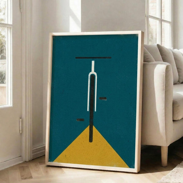 May include: Framed minimalist poster with teal blue background and geometric bicycle design in white and black with yellow triangle accent, displayed in bright living room next to beige sofa with natural lighting from large windows