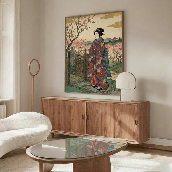 May include: Japanese woodblock print style artwork displayed above wooden credenza in modern living room. Print features woman in colorful traditional kimono with purple, red and blue patterns standing by garden gate, cherry blossoms and mountains in background. White sculptural chair and glass coffee table with wood base visible. White table lamp on credenza.