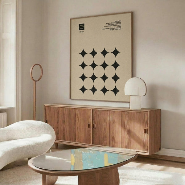 May include: Framed geometric poster with cream background featuring black circles and diamond pattern, displayed above wooden credenza in minimalist living room with white curved chair, brass floor lamp, glass coffee table, and white table lamp